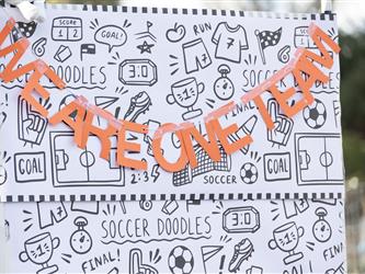 A sign with a black and white background and orange letters reads "We are one team".