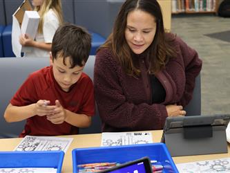 A boy and his mom work on a project at a table. 