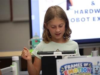 A girl with a mint green shirt stares at a tablet. 