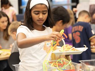 A girl stacks up colorful pipe cleaners. 