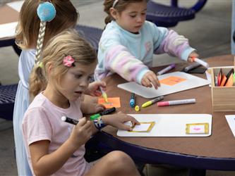 Children at a table color on paper. 